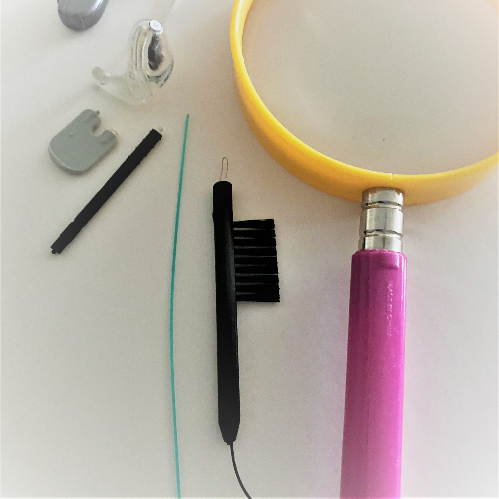 cleaning tools to maintain hearing aids, wax-guards and magnifying glass