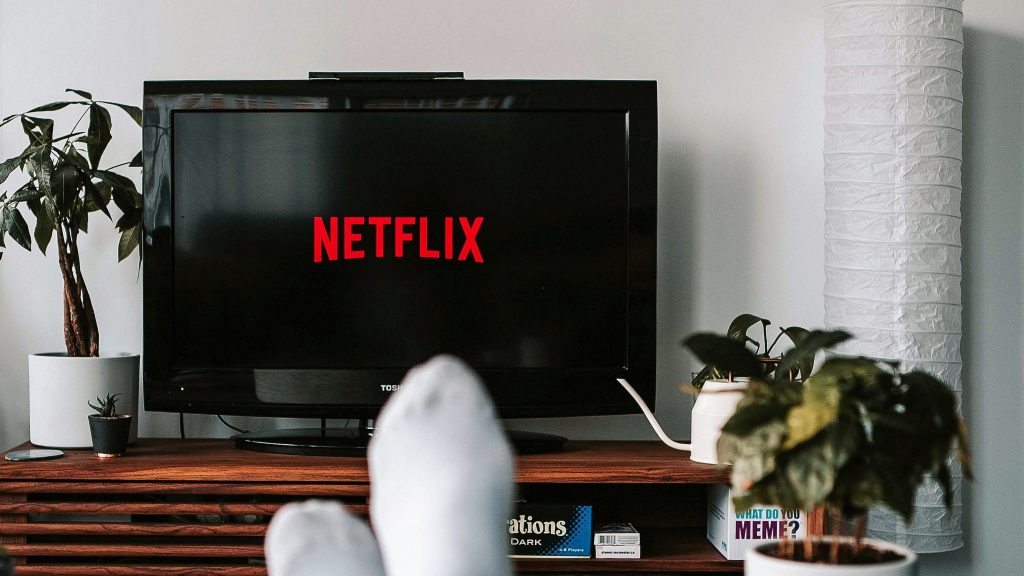 a television displaying Netflix title with viewer's feet in foreground where someone might need television enhancements for hearing loss