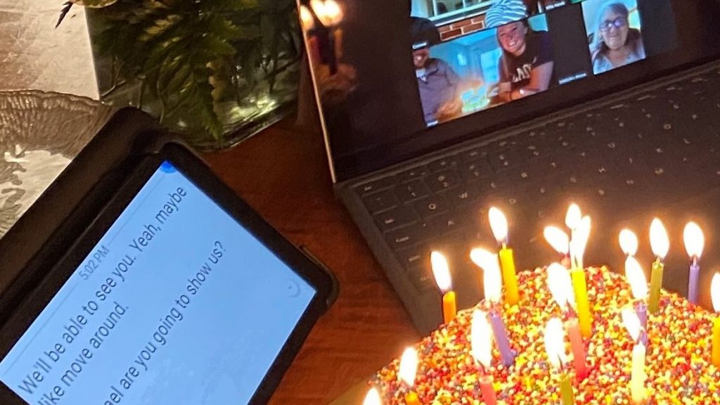 lit birthday cake next to zoom meeting on laptop and captions on tablet to fully engage in video conferences