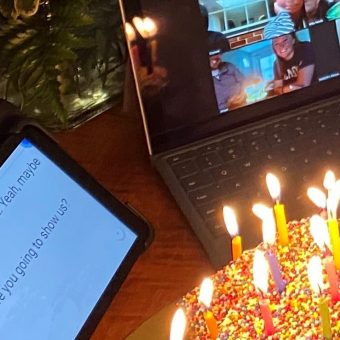 lit birthday cake next to zoom meeting on laptop and captions on tablet to fully engage in video conferences