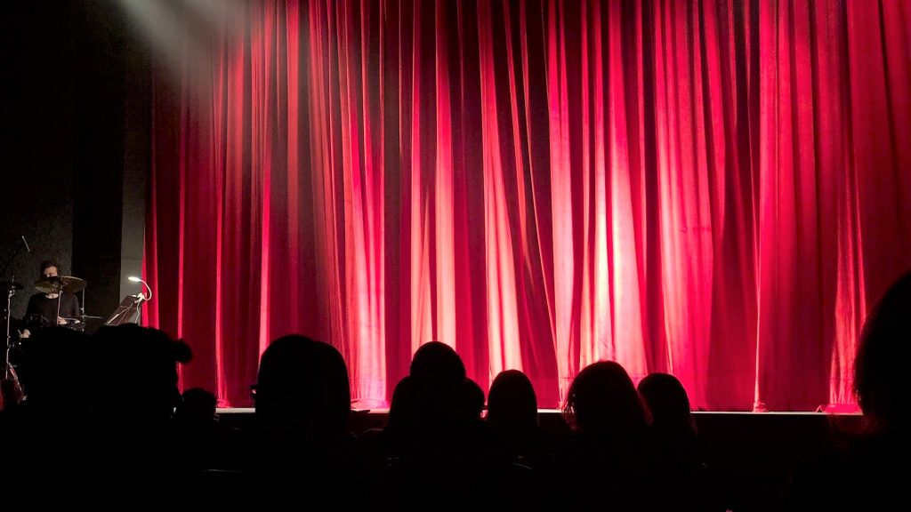 red theater curtain and audience in silhouette to represent hearing advocacy in public places