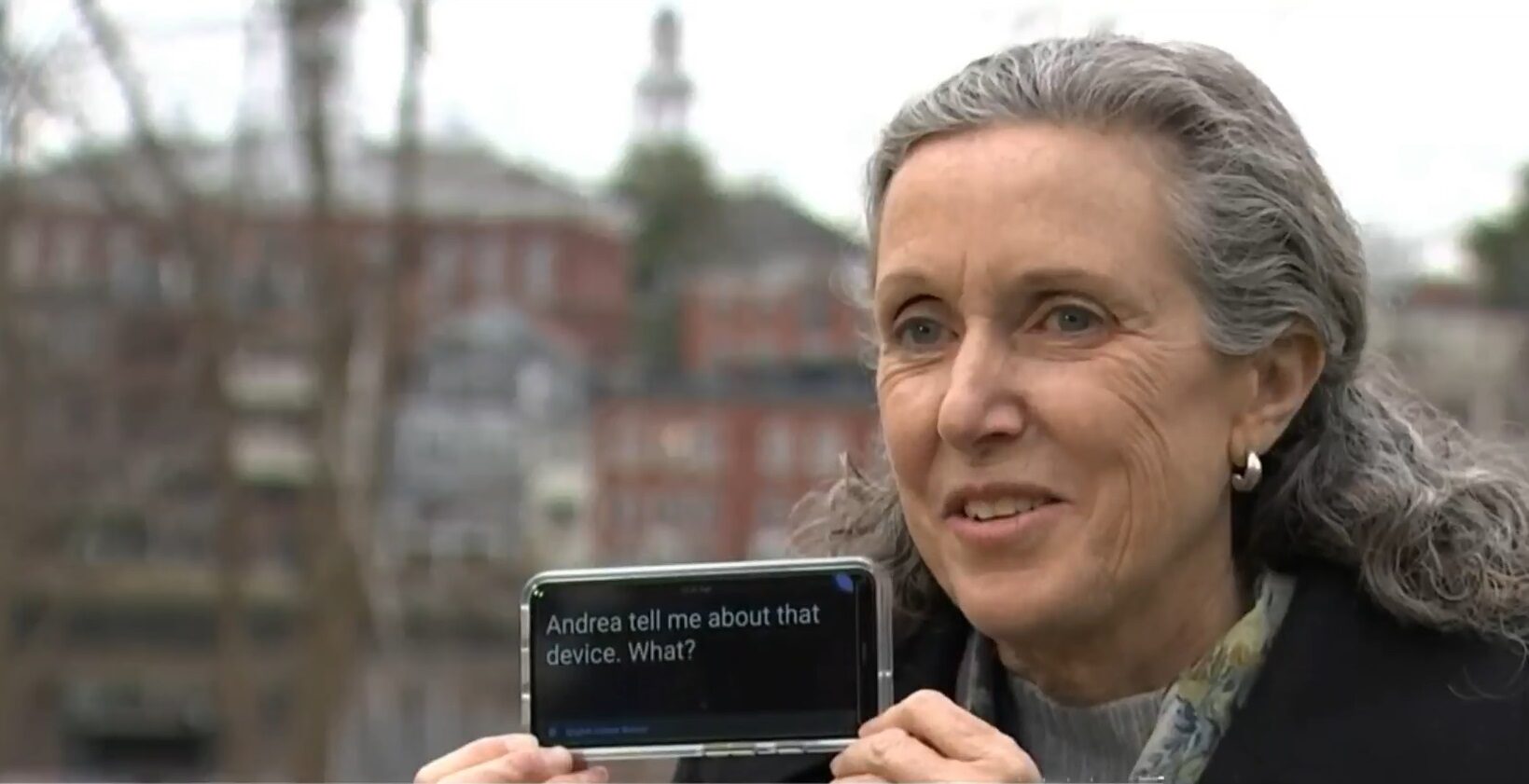 woman outside displaying a phone that has captions on it