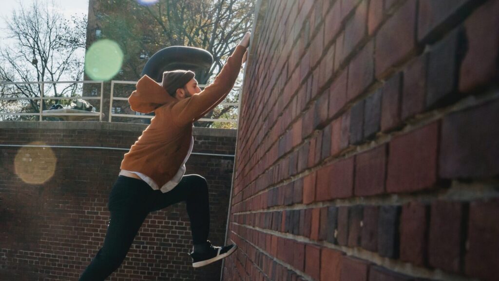 young boy tyring to climb up a brick well with one foot extended
